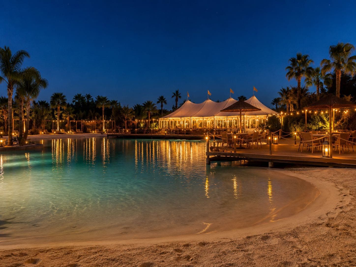 Lagon privé et pavillons illuminés à la nuit tombée dans la palmeraie de Marrakech
