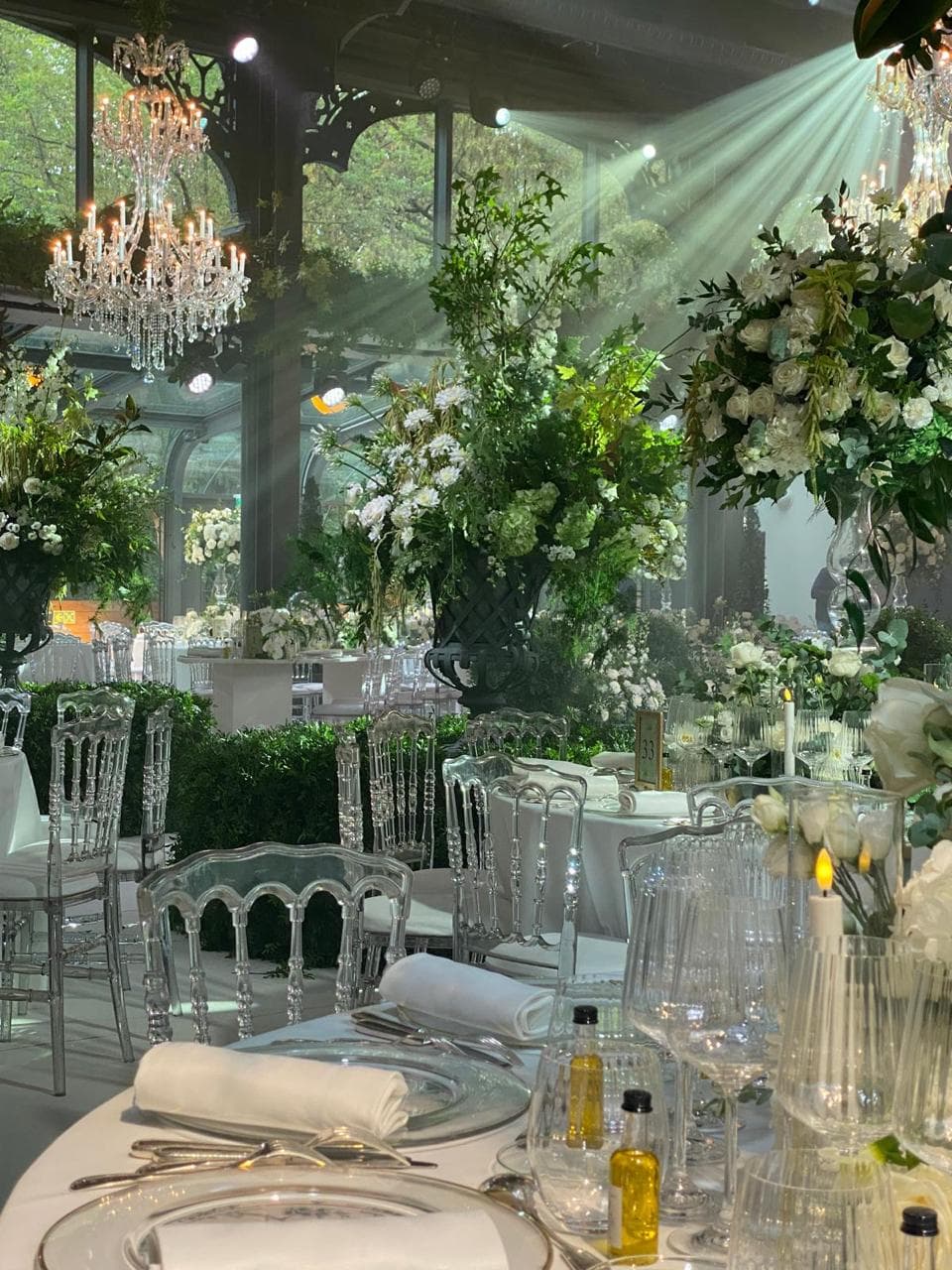 Composition de roses blanches et de verdure sous verrière avec lustre en cristal