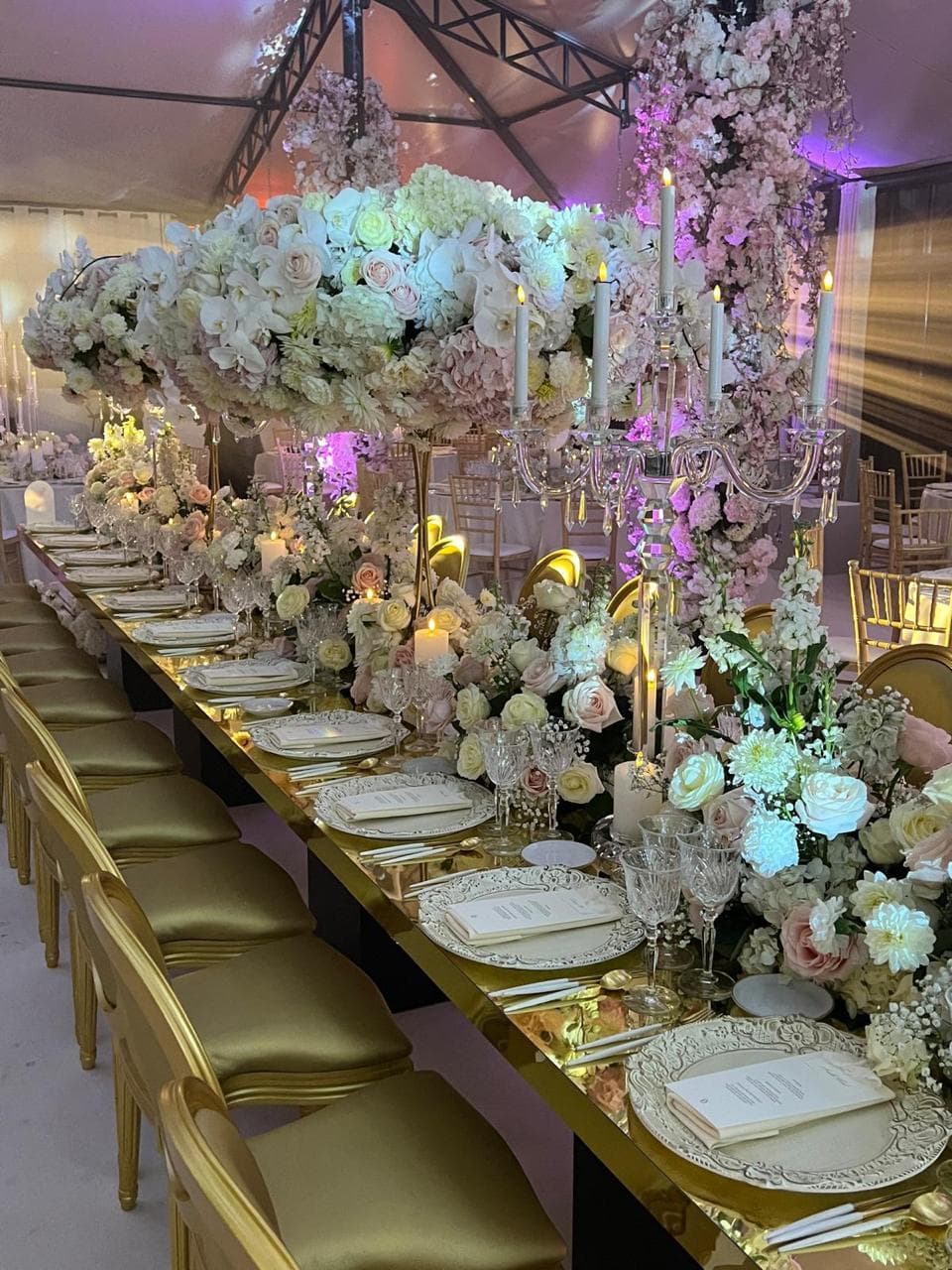 Longue table de mariage dorée aux compositions florales blanches et roses