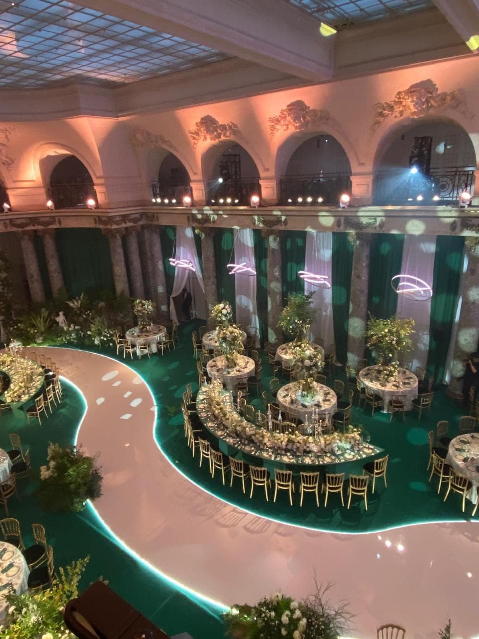 Salle de réception avec grands lustres, plafond monumental et tables rondes élégamment dressées