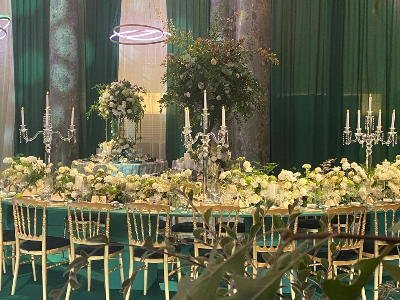 Table de réception luxueuse avec chandeliers en cristal, compositions florales et velours émeraude