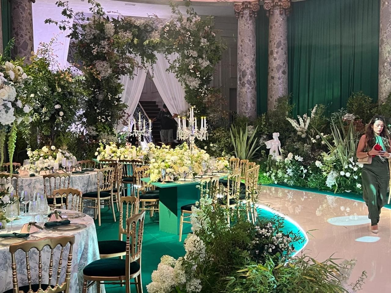 Wedding planner coordonnant la mise en place d’une réception de mariage parmi les décors floraux