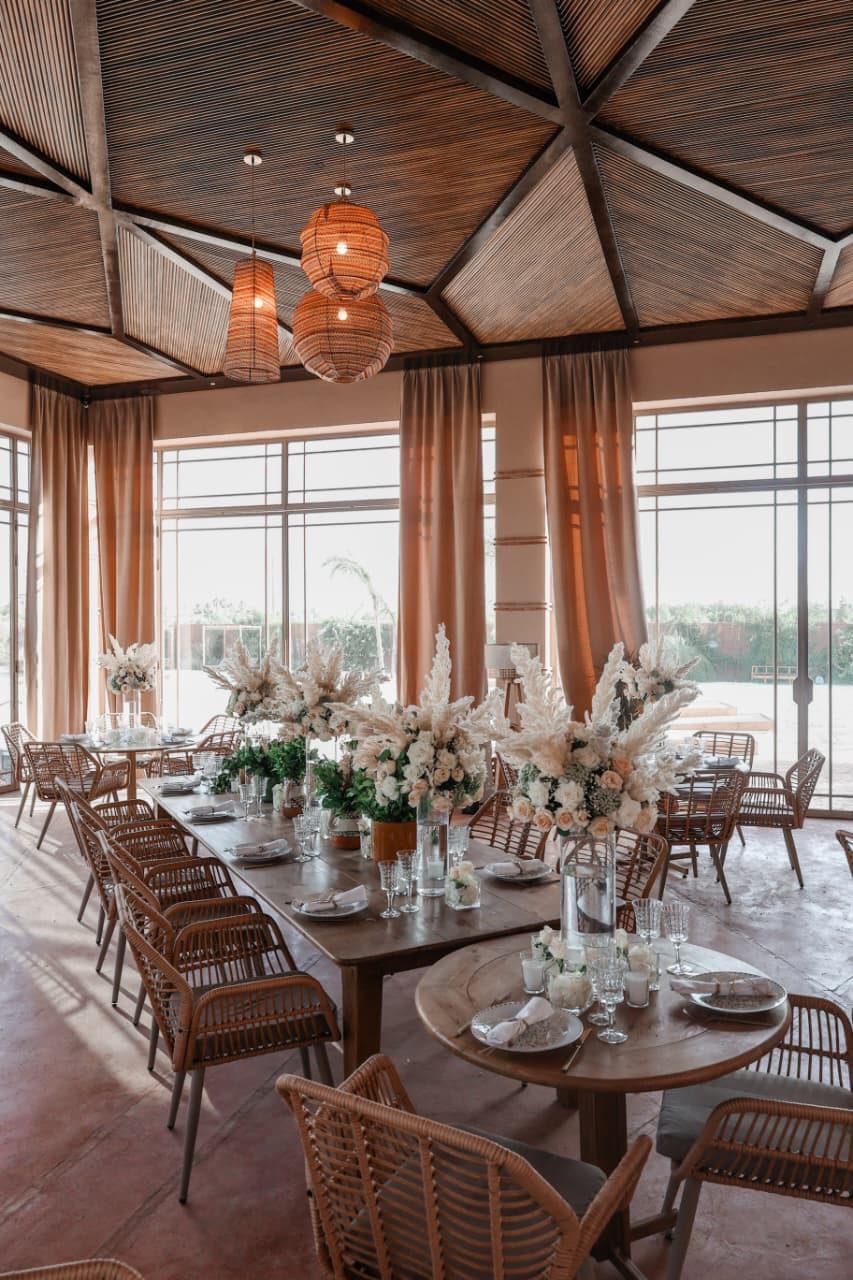 Salle de réception bohème avec longues tables en bois, rotin et suspensions tressées